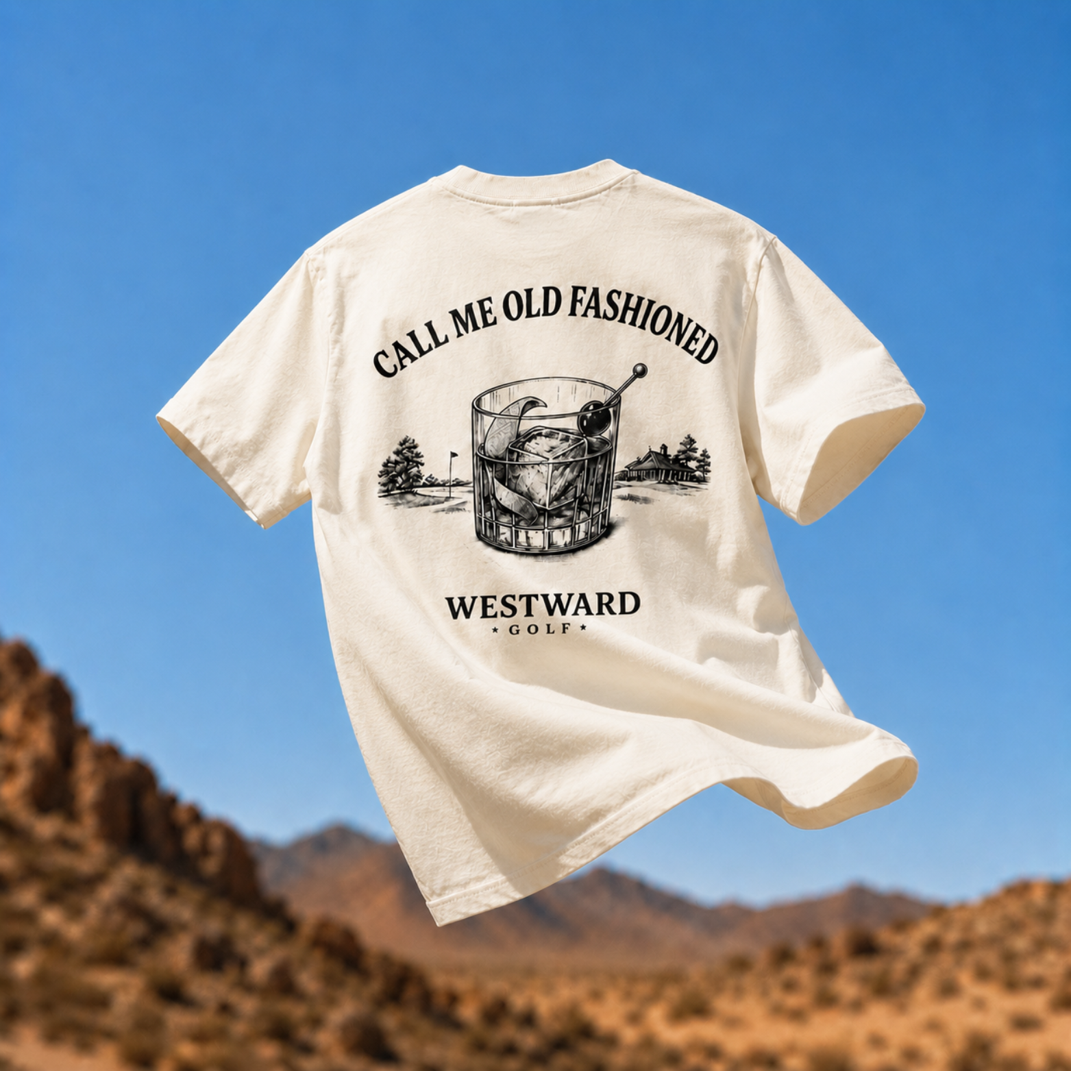 Cream Westward Golf old fashioned graphic t-shirt floating over desert mountains with cocktail glass artwork, golf course scenery, and CALL ME OLD FASHIONED back print