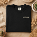 Folded black Westward Golf t-shirt with small cream front chest logo on neutral flat lay background with desert-inspired styling
