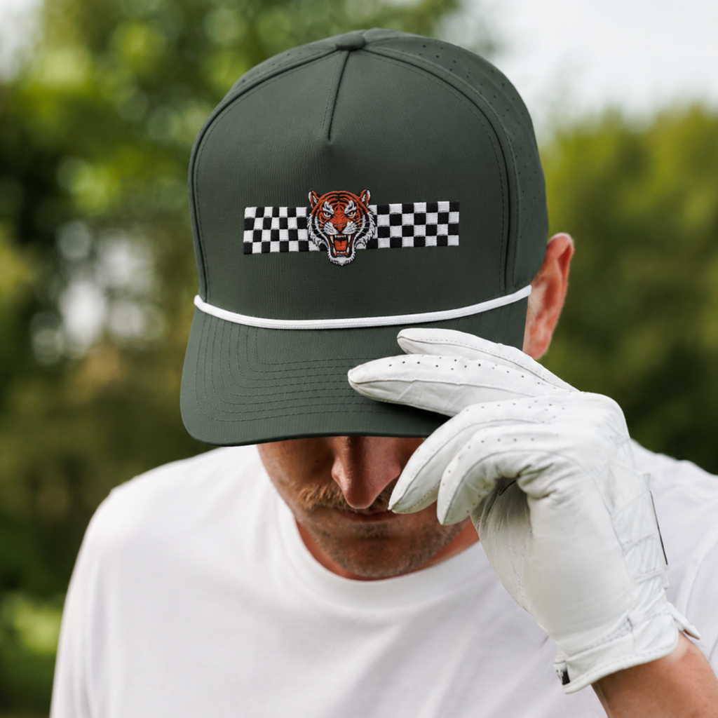Golfer wearing a green cap with a tiger logo and checkered pattern, holding a white golf glove.