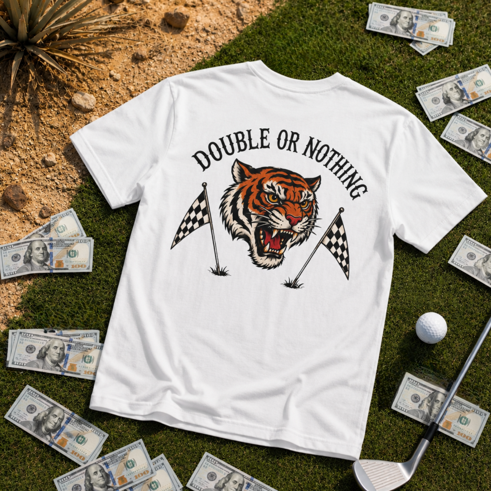 White Double or Nothing golf graphic t-shirt laid flat on grass with oversized roaring tiger back print, checkered golf flags, golf ball, iron club, scattered cash, and vintage golf betting streetwear style.