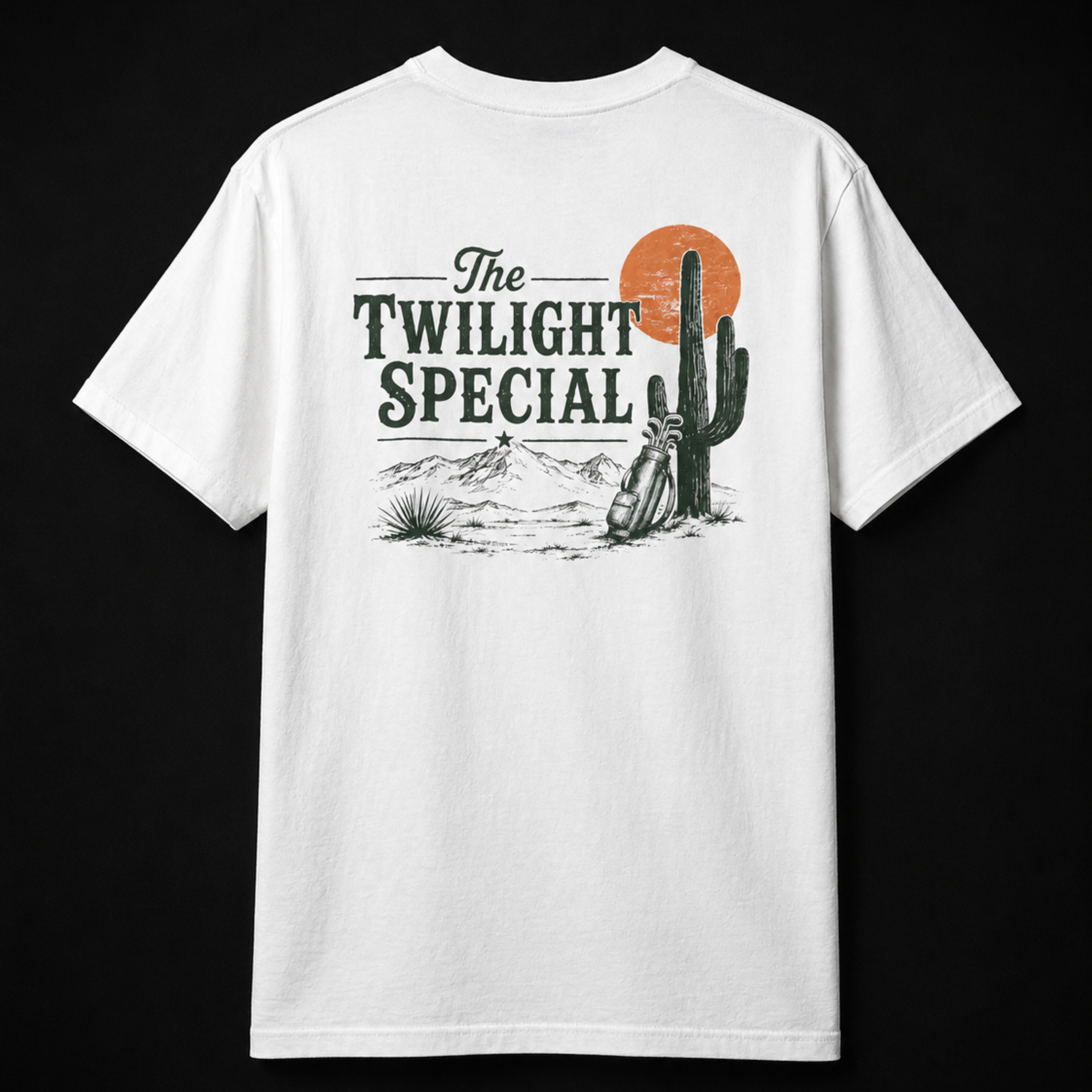 White Westward Golf “The Twilight Special” back graphic T-shirt mockup on black studio background, featuring vintage desert golf artwork with green lettering, cactus, orange sunset, mountains, and golf bag design.